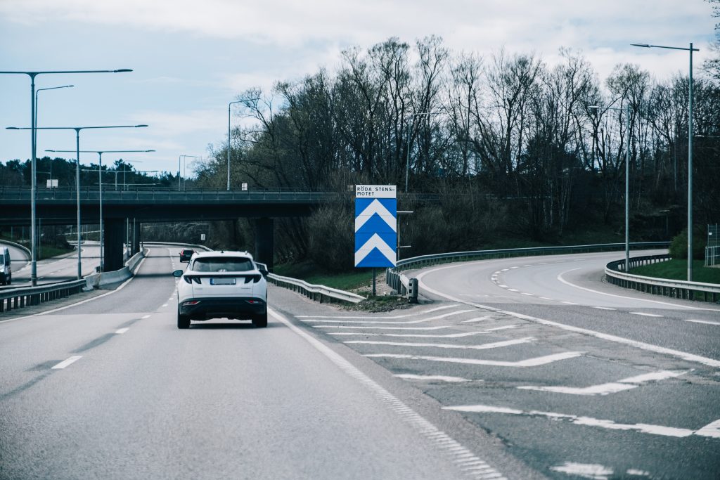Två personbilar kör förbi en skylt där det står Rödastensmotet