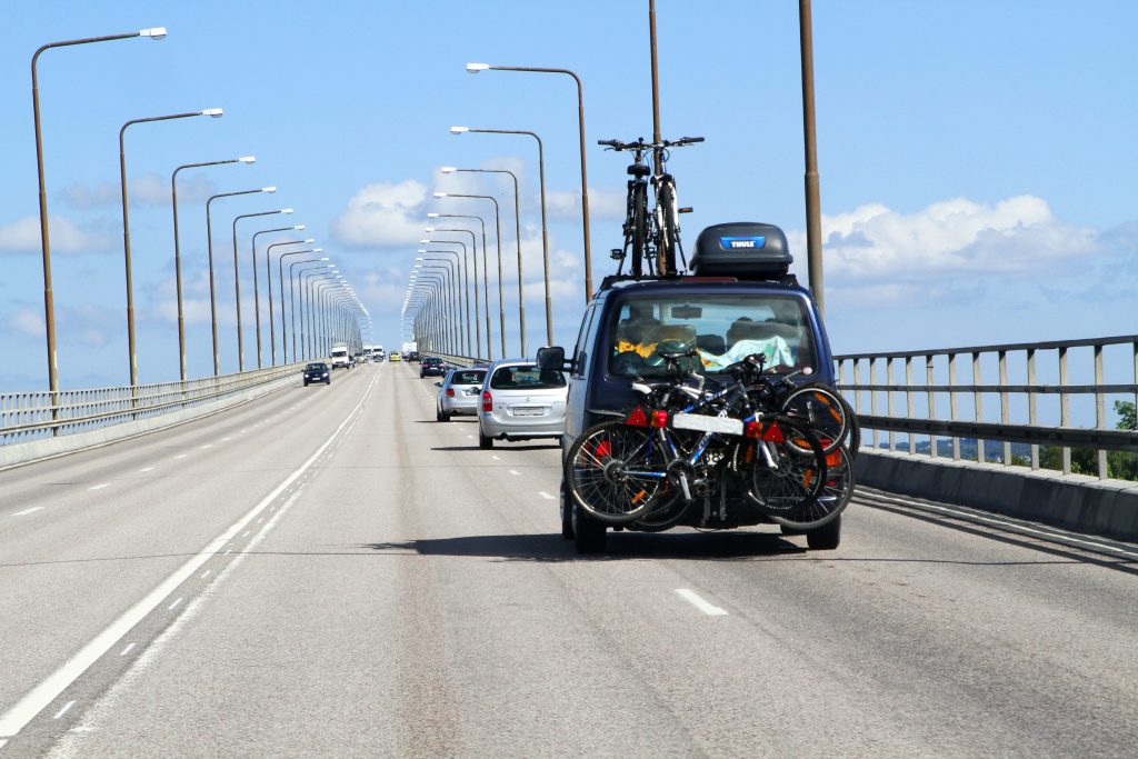 En fullpackadbil med cyklar och takbox kör upp på Ölandsbron på väg mot Öland.