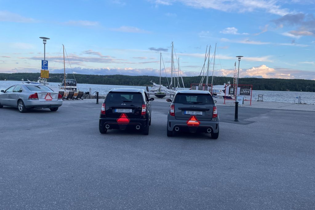 En A-traktor och två mopedbilar står parkerade vid en kaj.