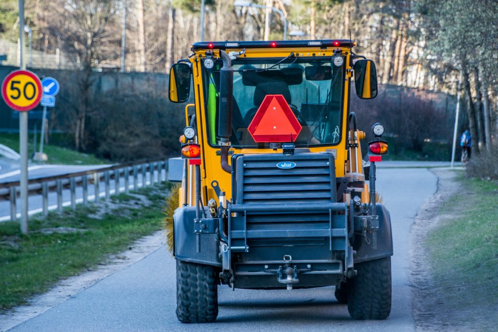 En sopmskin vårstädar längs en cykelbana.